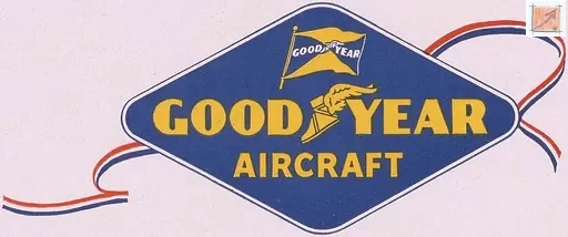 Ein blaues, rautenförmiges Werbeschild mit der gelben Aufschrift „Goodyear Aircraft“. Das Logo ist festlich mit rot-blauen Bändern dekoriert, die wie Luftschlangen wirken. Es markiert die Ära, in der Goodyear durch die Übernahme deutscher Zeppelin-Technologie zum Luftfahrtgiganten aufstieg.