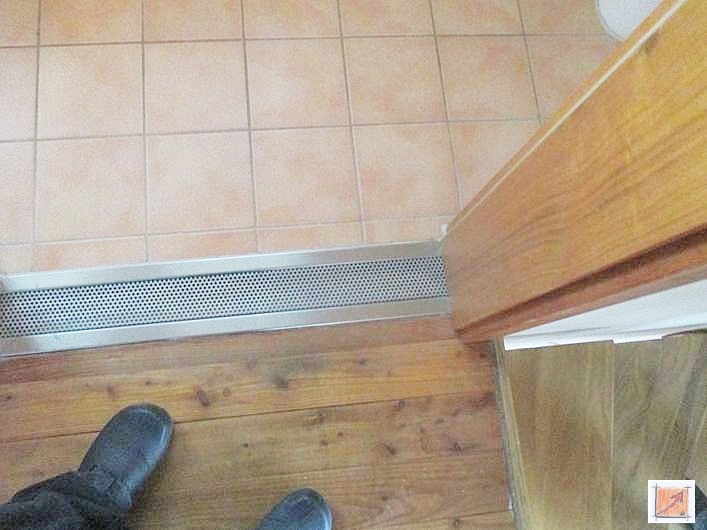 Ästhetik trifft Funktion: Präzise handwerkliche Fertigung der Sicherheitsrinne. Detailaufnahme einer hochwertig verarbeiteten Edelstahlrinne mit dekorativem Lochmuster im Übergang zum Holzboden.